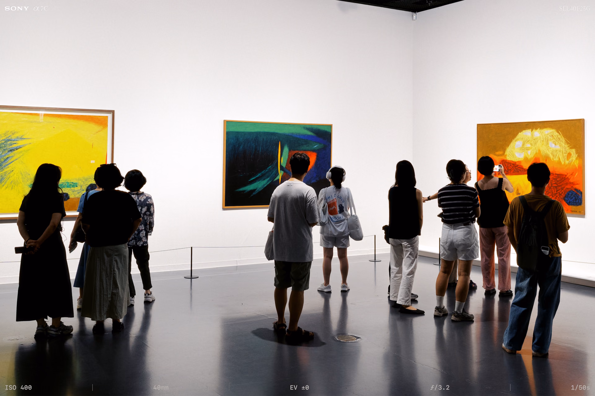 People gathered before the paintings in a corner of the room