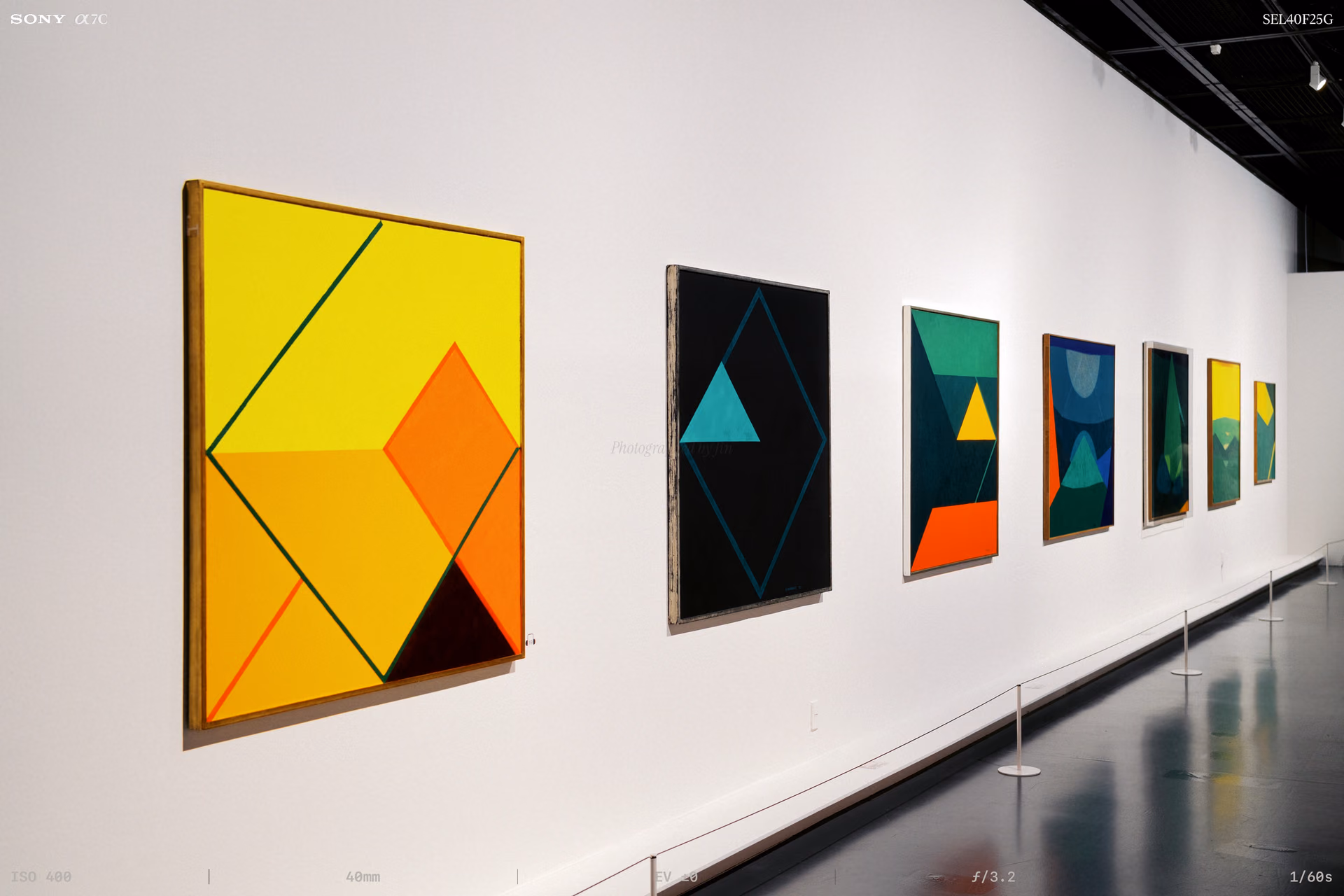 Paintings hung in a row along a long white wall