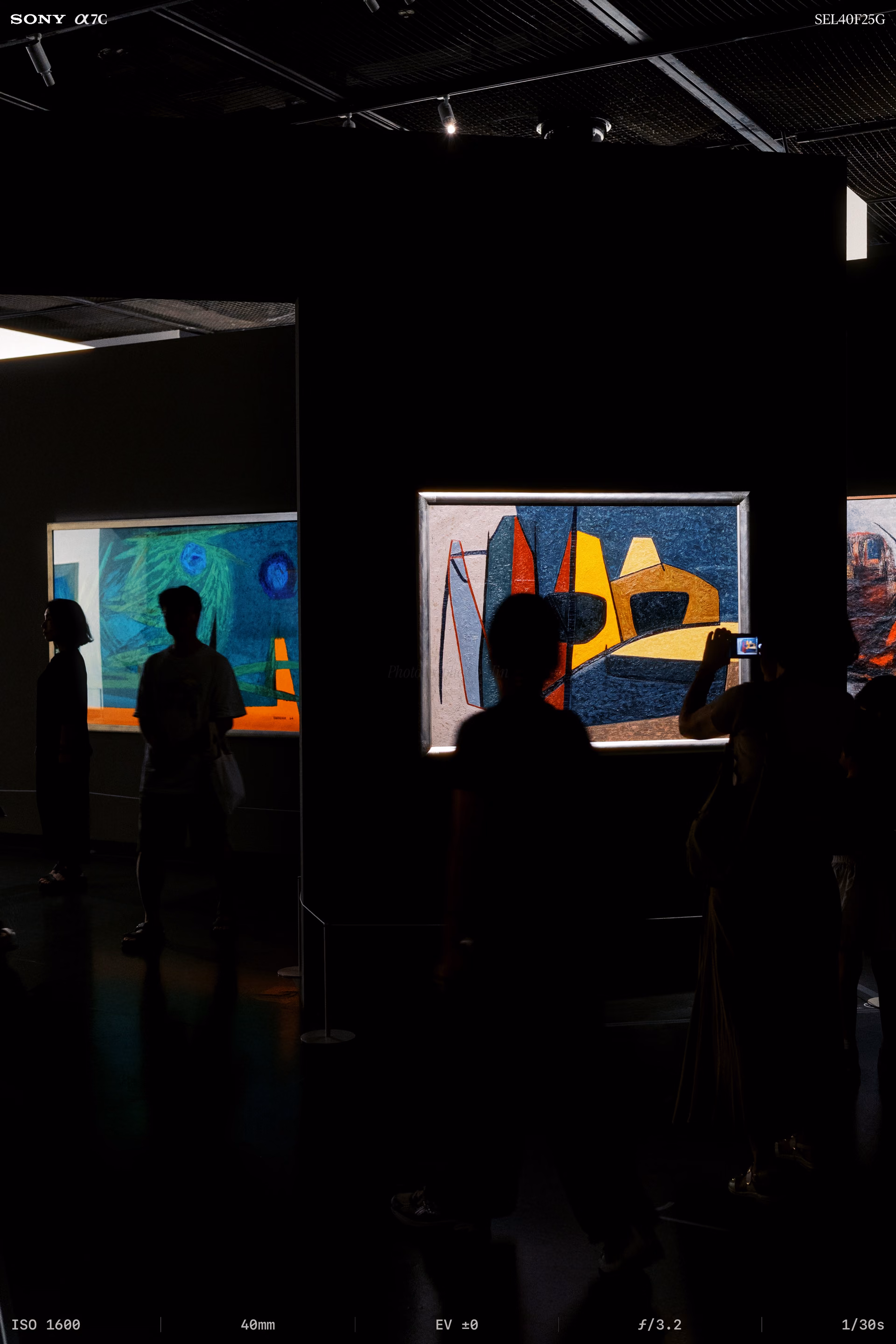 Someone photographing an angular painting under a spotlight